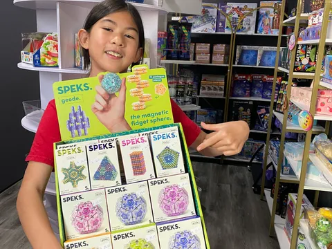 A young shopper holding a SPEKS magnetic fidget sphere display at Mindspace Toys, part of our selection for tweens, teens, and adults.